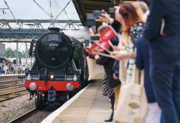 Guests look on as Flying Scotsman arrives at Doncaster Railway Station, celebrating her centenary by making a return to the city where she was built one hundred years ago, at an event hosted by City of Doncaster Council and London North Eastern Railway (LNER), which also turns 100 this year. Picture date: Friday June 30, 2023. PA Photo. In 1923, the steam locomotive was the first to be built at the Doncaster Works by the then newly formed LNER, costing £7,944 to build, and in its 40-years of service broke numerous world speed and distance records, including being the first locomotive to reach 100mph, and the first to circumnavigate the globe.