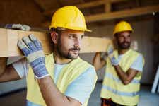 Two construction workers carrying building materials