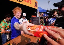 Ed Sheeran hands out ‘Handy Tingly Pies’, a new collaboration between Ed Sheeran’s hot sauce brand, Tingly Ted’s and Pieminister, which make their debut at today’s Ipswich Town Football Club home match against Liverpool, the first home match since the club’s recent promotion to the Premier League. Picture date: Saturday August 17, 2024. PA Photo. To mark Ipswich’s 203rd Premier League game (but its first for 22 years), 203 meat and 203 vegetarian ‘Handy Tingly Pie’ pies will be given away for free to fans during the fixture at Portman Road. Ed Sheeran is Ipswich Town Football Club’s headline sponsor, and has just announced a minority stake in the team.