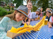 Lexi Urhammer, 10, from London holds up a 12.12m long bratwurst created by Seared Pubs in Droitwich Spa to celebrate the launch of its Oktoberfest menu. Issue date: Sunday September 22, 2024. PA Photo. Complete with crispy onions and curry ketchup, the bratwurst represents the 1,212km between the pub and Theresienwiese, Munich, the home of Oktoberfest.