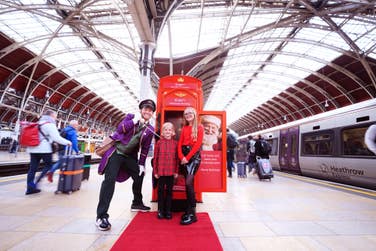 EDITORIAL USE ONLY Joe Swash dresses as a Bellboy, surprises Dolcie Fleur Simmons, aged 12, and her brother Jimmy-Judson Simmons, aged 8, and Heathrow Express passengers at Paddington Station as part of the launch of the ‘HeXmas Hotline’, a service by the airport rail link provider to help connect passengers to Father Christmas and their loved ones this festive season. Picture date: Monday December 9, 2024. PA Photo. The HeXmas Hotline service, which takes the form of a vintage red telephone box, will be stationed at Heathrow Express platform at Paddington Station between 9am - 3pm, December 9th - 20th, allowing passengers to ‘call Santa’ and record and festive video and card greetings letting loved ones know they’re on their way home for the holidays.