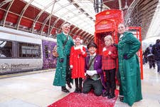 EDITORIAL USE ONLY Joe Swash dresses as a Bellboy, seen with his assistant bellboys Lucy Smith and Fay Sharp, and surprises Marcie-Mayve Simmons and her brother Jimmy-Judson Simmons , both aged 8, and Heathrow Express passengers at Paddington Station as part of the launch of the ‘HeXmas Hotline’, a service by the airport rail link provider to help connect passengers to Father Christmas and their loved ones this festive season. Picture date: Monday December 9, 2024. PA Photo. The HeXmas Hotline service, which takes the form of a vintage red telephone box, will be stationed at Heathrow Express platform at Paddington Station between 9am - 3pm, December 9th - 20th, allowing passengers to ‘call Santa’ and record and festive video and card greetings letting loved ones know they’re on their way home for the holidays.