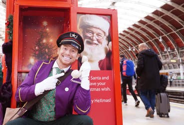 EDITORIAL USE ONLY Joe Swash dresses as a Bellboy and surprises Heathrow Express passengers at Paddington Station as part of the launch of the ‘HeXmas Hotline’, a service by the airport rail link provider to help connect passengers to Father Christmas and their loved ones this festive season. Picture date: Monday December 9, 2024. PA Photo. The HeXmas Hotline service, which takes the form of a vintage red telephone box, will be stationed at Heathrow Express platform at Paddington Station between 9am - 3pm, December 9th - 20th, allowing passengers to ‘call Santa’ and record and festive video and card greetings letting loved ones know they’re on their way home for the holidays.