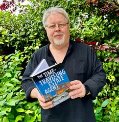 Author Dale Bradford, holding his novel, The Time-Travelling Estate Agent