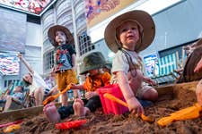 EDITORIAL USE ONLYOscar, aged 4, Alex, aged 2 and Ed, aged 2, in a sand pit at Summer Safari, a free immersive experience at Printworks in Manchester, designed to entertain and educate children throughout the summer holidays. Picture date: Thursday July 23, 2026. PA Photo. To celebrate the launch today, Printworks is hosting workshops, life-size animal puppet parades and interactive play zones.